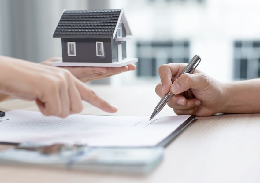signing-paper-with-someone-handing-wooden-home