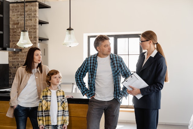 a family in a kitchen with someone in a suit