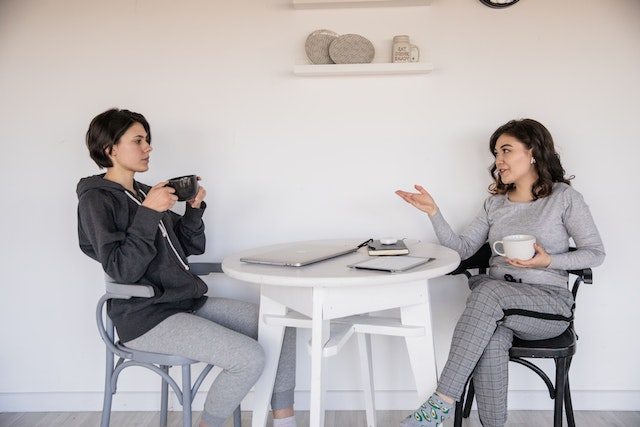 two people sitting at a white table having a conversation