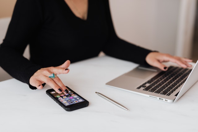 someone on a phone next to a laptop