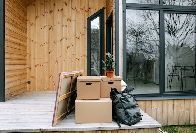  moving boxes, a bag, plant, and painting, sitting on a front porch