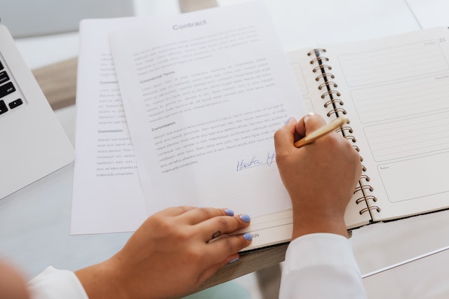 someone signing a document with a pen