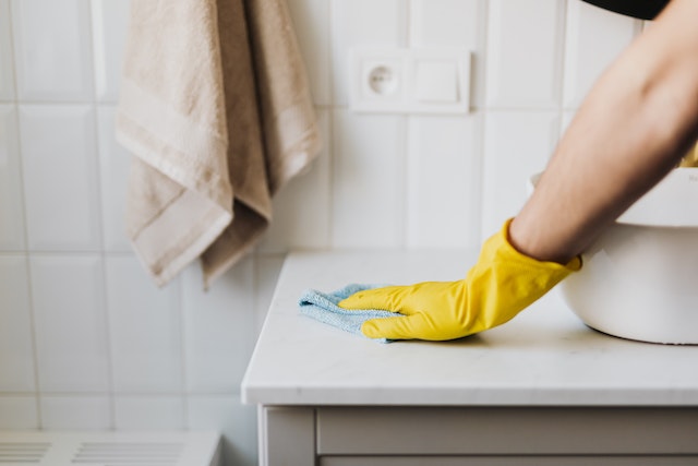 a gloved hand wiping down a bathroom counter