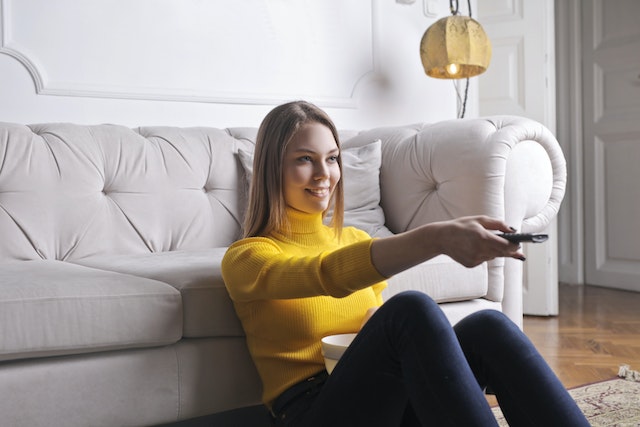 a person sitting on the ground pointing a remote control