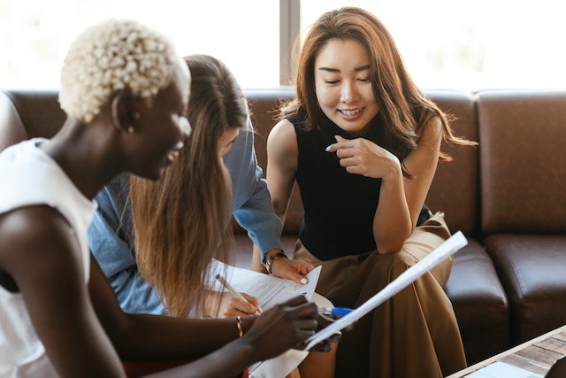 three people looking at papers on a couch