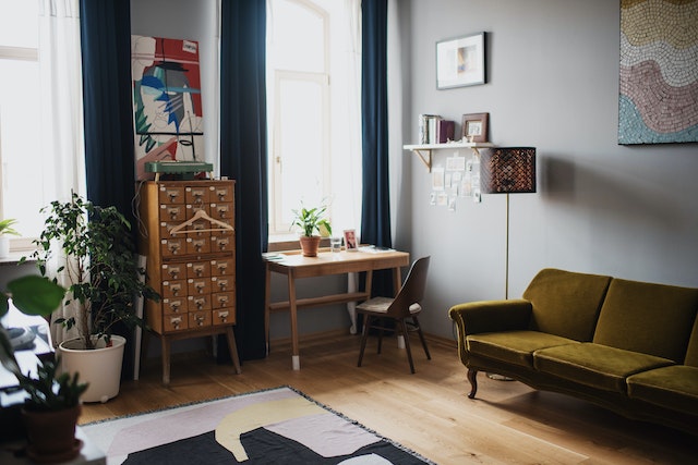 a fully furnished room with a desk, rug, sofa, and shelves