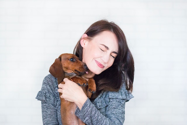 standing and hugging a weiner dog
