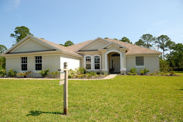 A house with a for sale sign on the front lawn